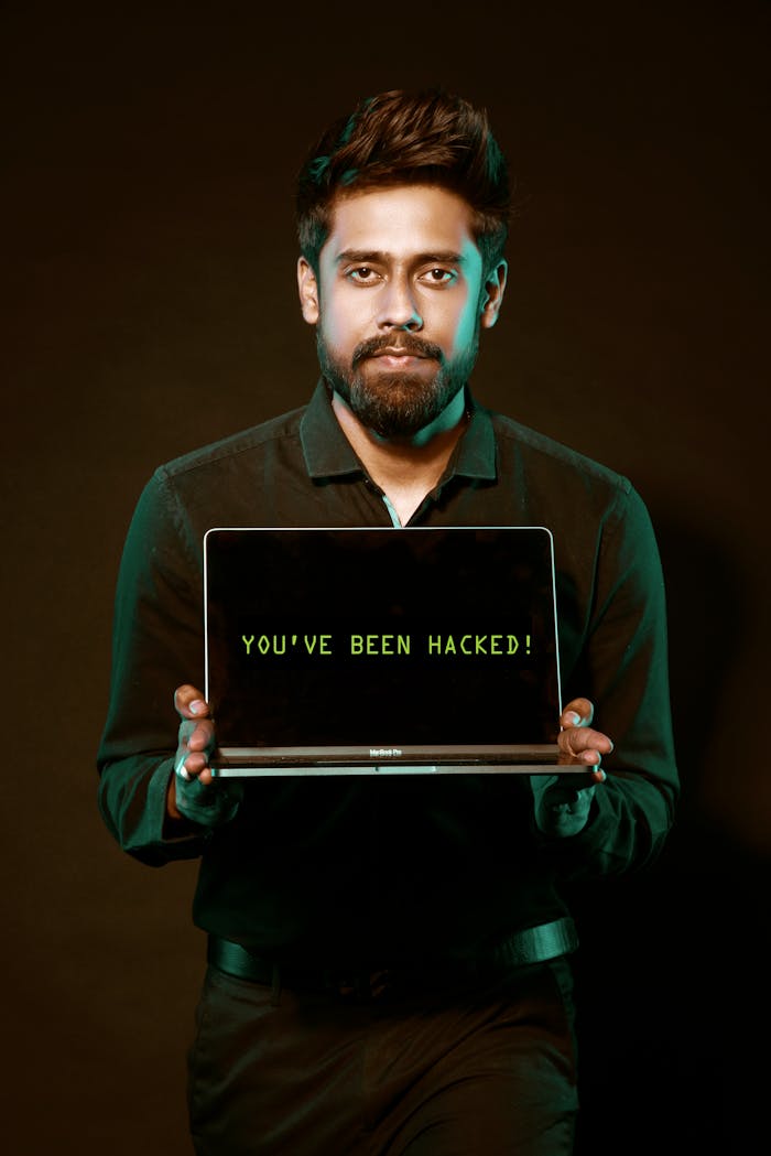 A man showing a laptop with a 'You've been hacked' message, symbolizing cyber security threats.