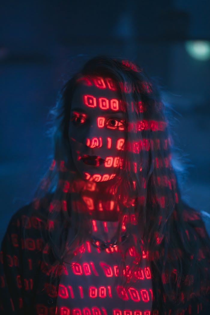 services-01 A woman with red binary code projected on her face, signifying technology and cybersecurity.